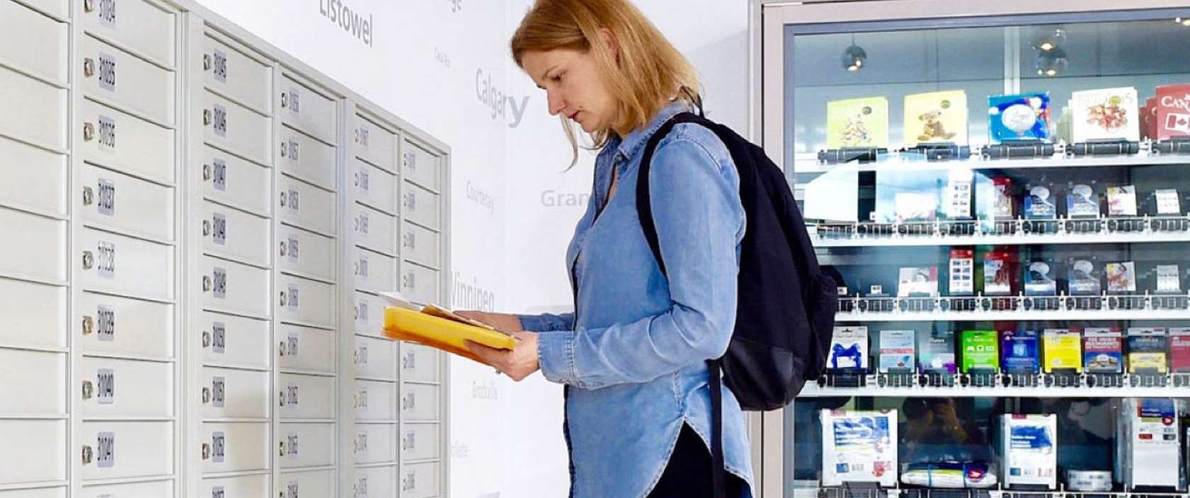 A woman inside a post office sorts through a small stack of mail she has just retrieved from her Canada Post PO box. 