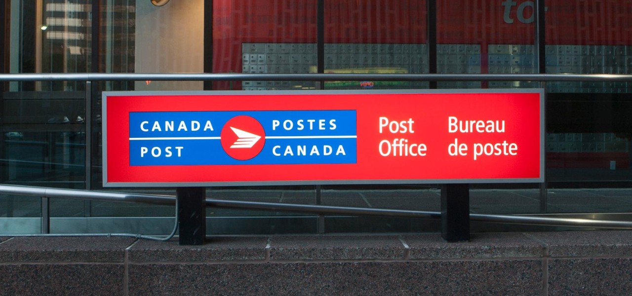 Gros plan d’une grande enseigne affichant le logo bilingue de Postes Canada