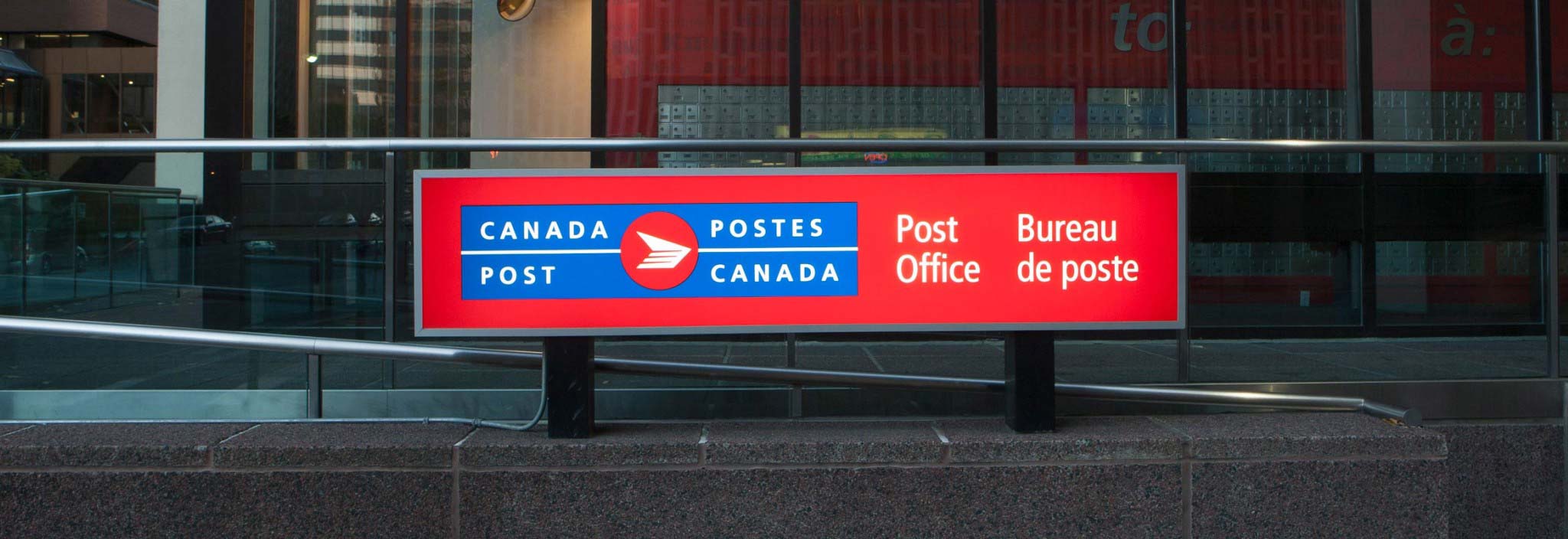 Gros plan d’une grande enseigne affichant le logo bilingue de Postes Canada