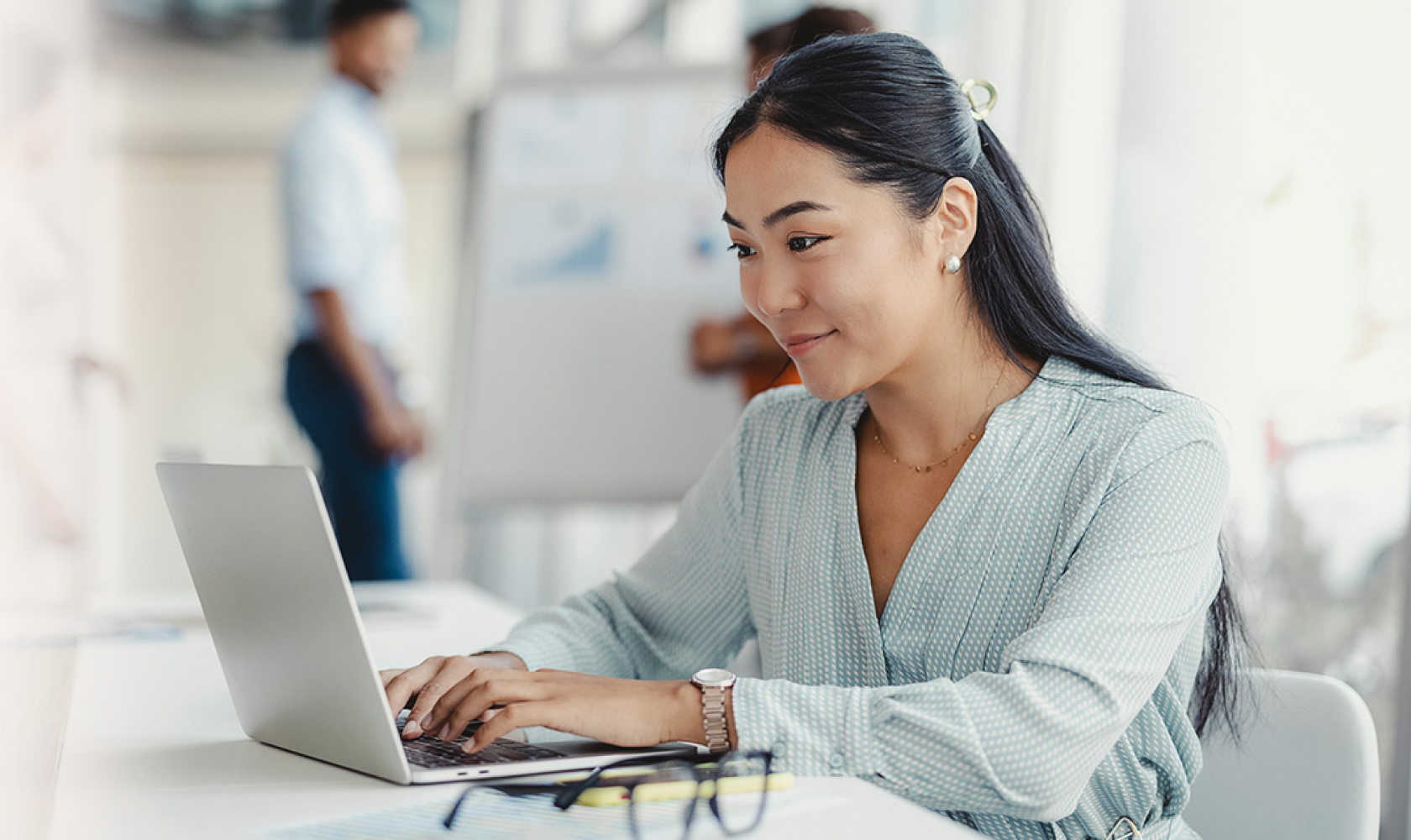 Une femme assise à une table de travail utilise un ordinateur portable