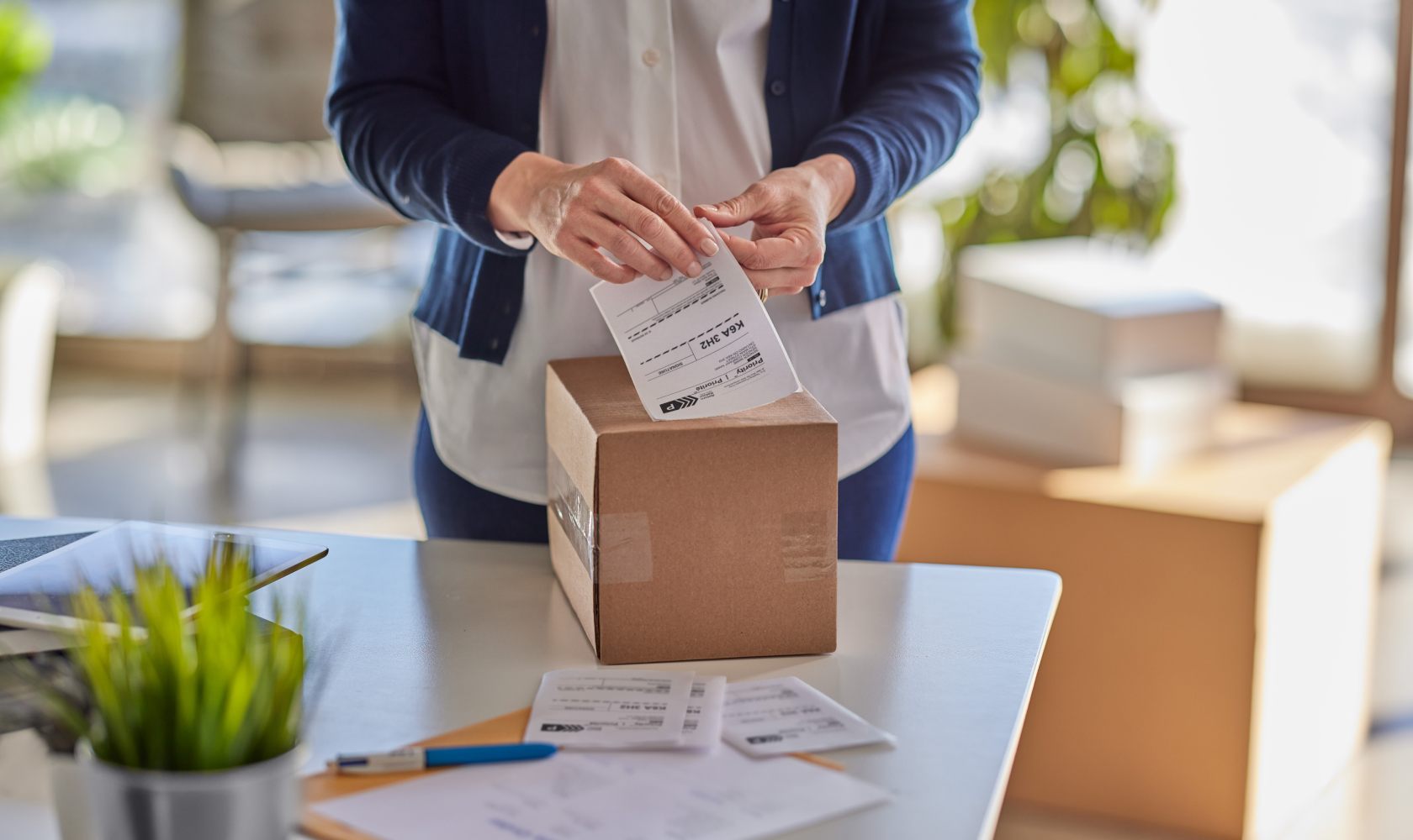 Une femme appose une étiquette d’expédition sur une boîte en carton.